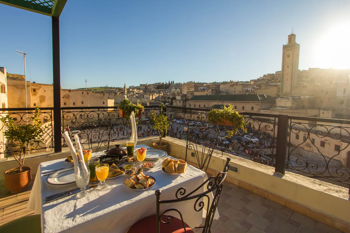 Petit-déjeuner marocain servi sur la terrasse : thé à la menthe, pâtisseries et fruits